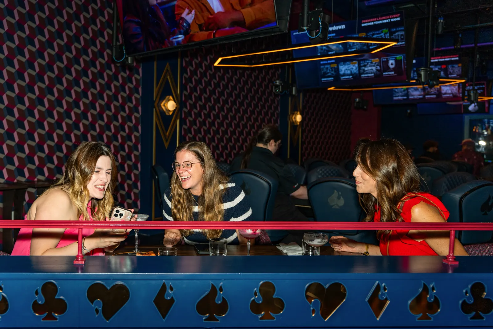 A group of friends laughing over drinks in a booth at Showdown Social