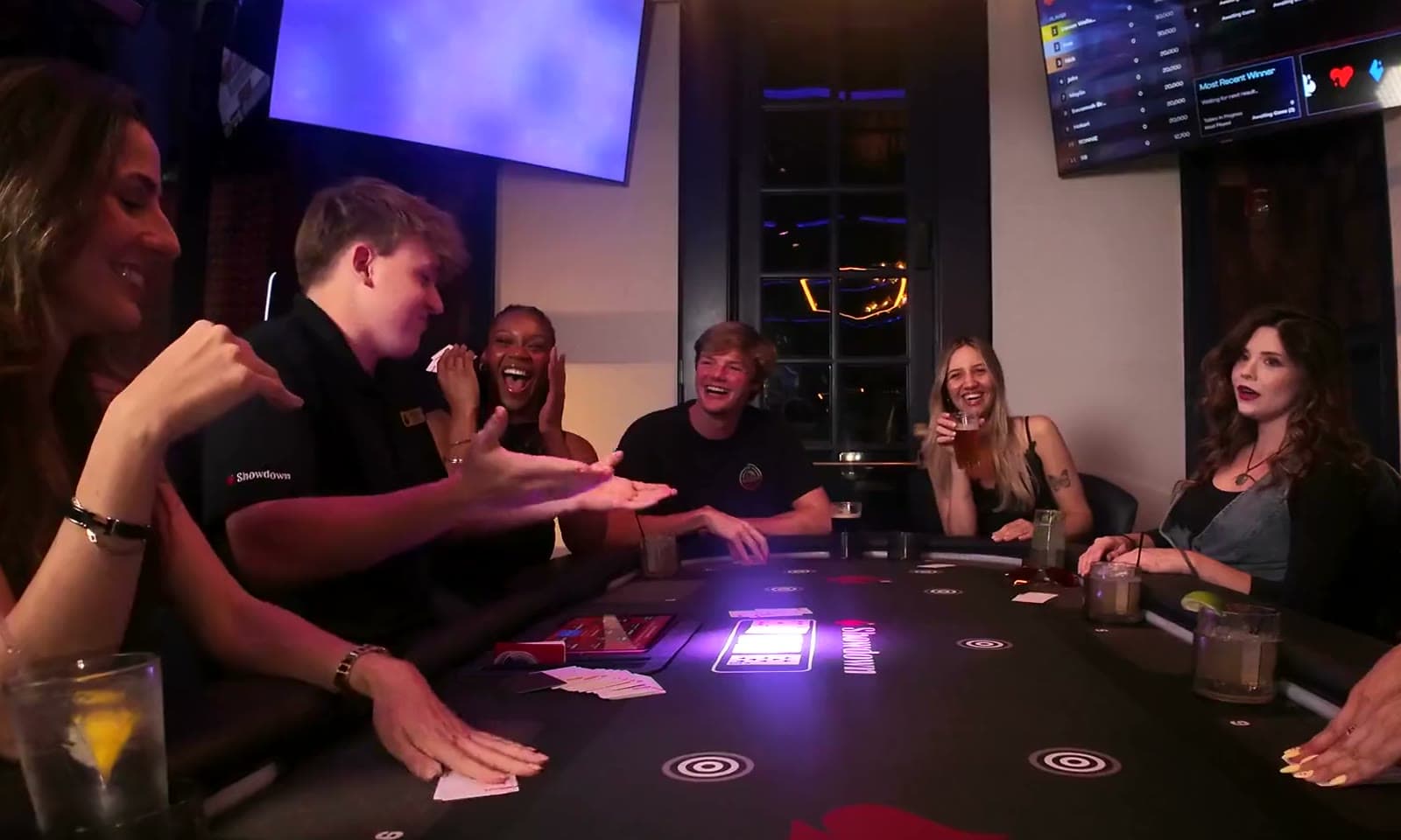 Women and friends reacting around a Showdown Social game table