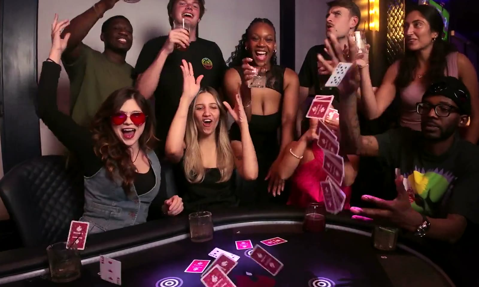 Friends laughing as cards fly above a glowing Showdown game table